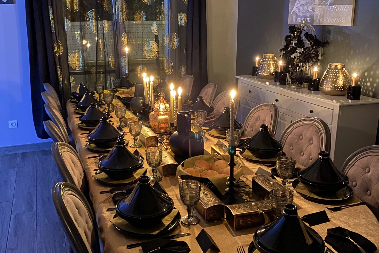 D'Or et d'Orient — grande table dressée aux tajines noirs, chandeliers, lanterne dorée et coffrets ciselés, scénographie EVEN'IN